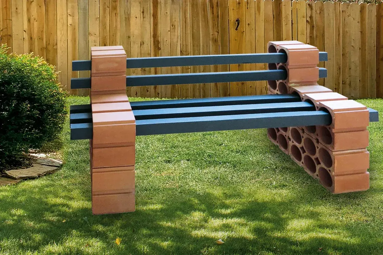 Eine rustikale Gartenbank, die man leicht selber bauen kann, mit Sitzflächen aus dunklen Balken und Stützen aus Ziegelsteinen.