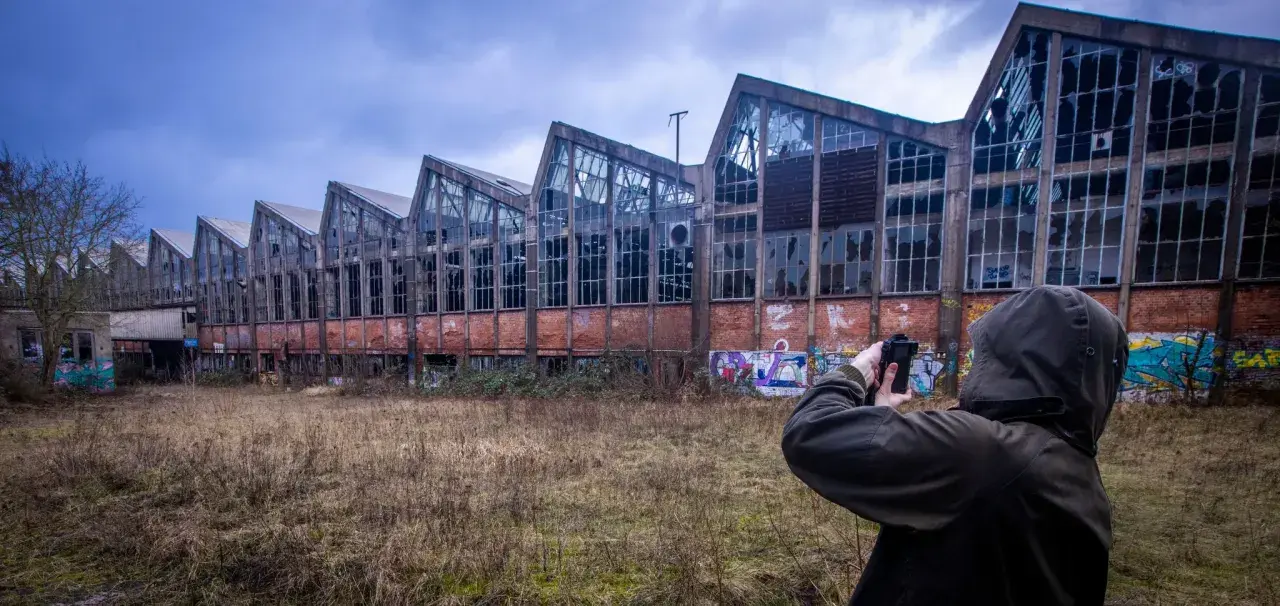 Exploration urbex à Angoulême : une silhouette capture l'architecture délabrée d'une usine abandonnée, ornée de graffitis.