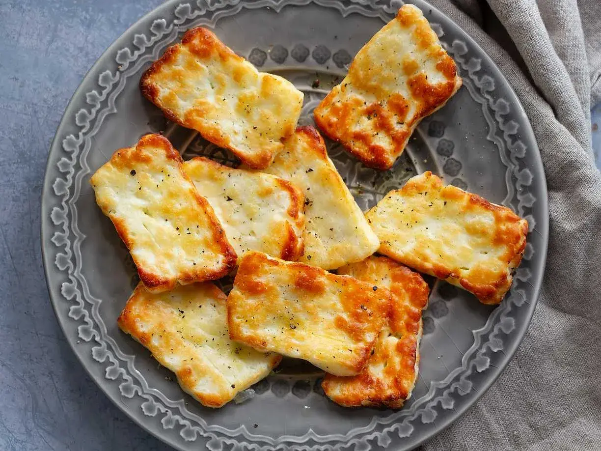 Gylla halloumi i airfryer, gyllene och krispiga bitar på en grå tallrik, kryddade med peppar.