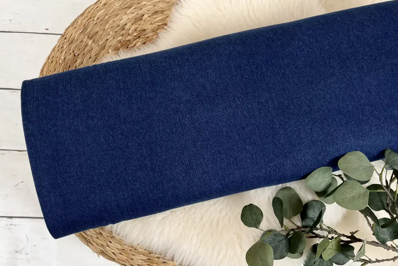 Dunkelblauer Denim-Stoff, aus dem Jeans gemacht sind, liegt auf einem Schaffell.