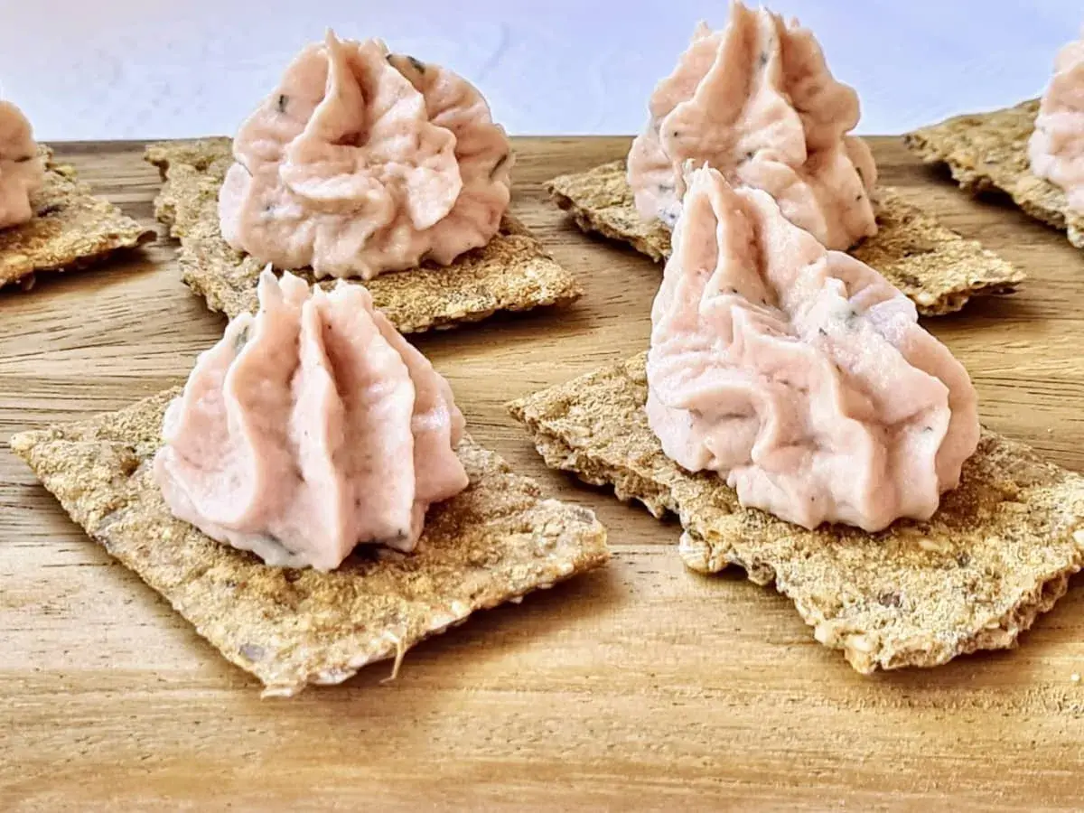 Petites bouchées de rillettes de jambon onctueuses sur des crackers croustillants, prêtes à être dégustées.