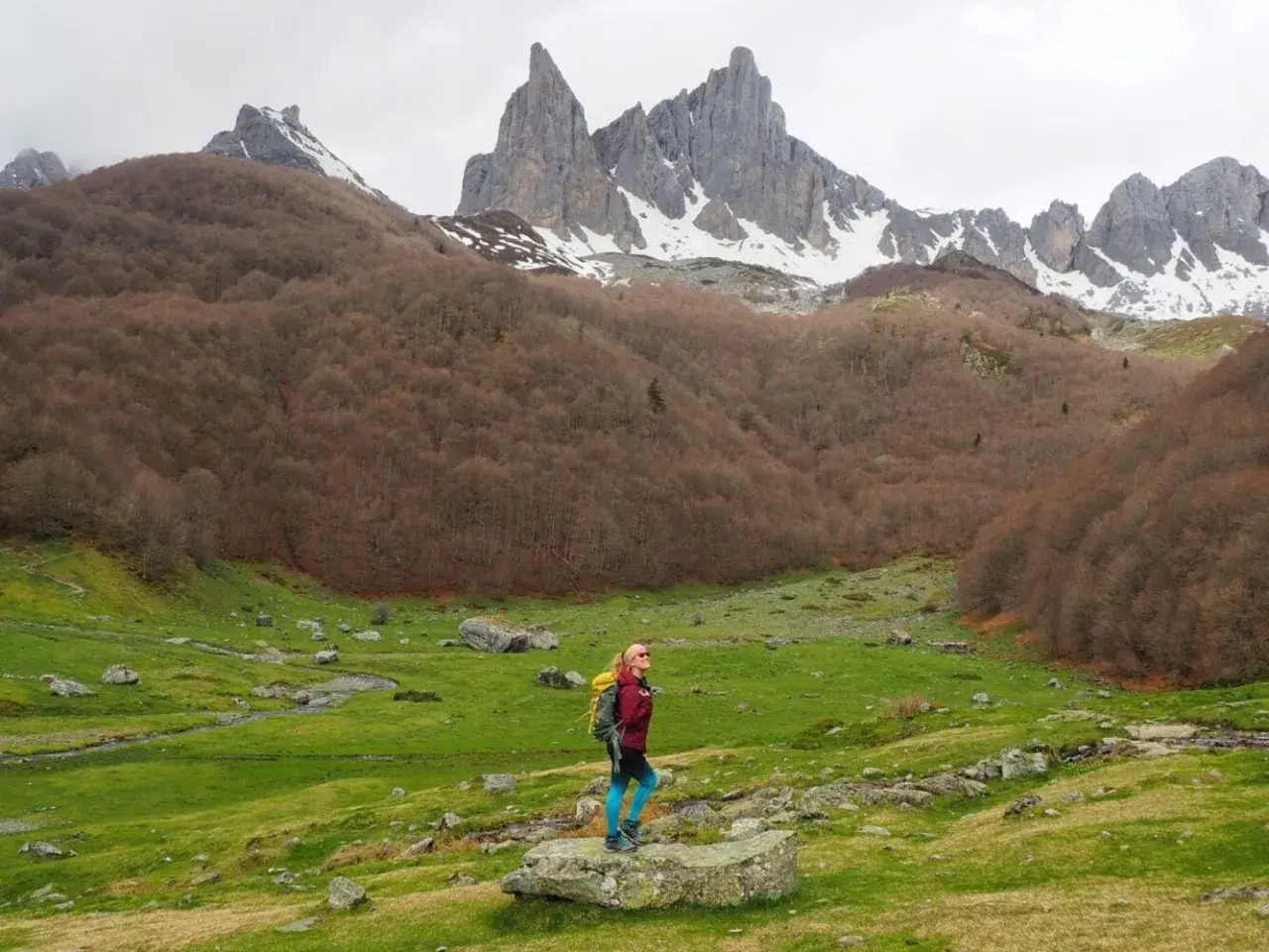 Senderista admira el majestuoso valle de Aspe, con picos nevados y bosques otoñales.
