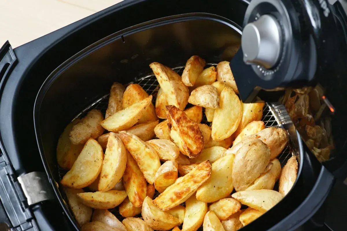 Patate a spicchi dorate e croccanti appena sfornate nella friggitrice ad aria.
