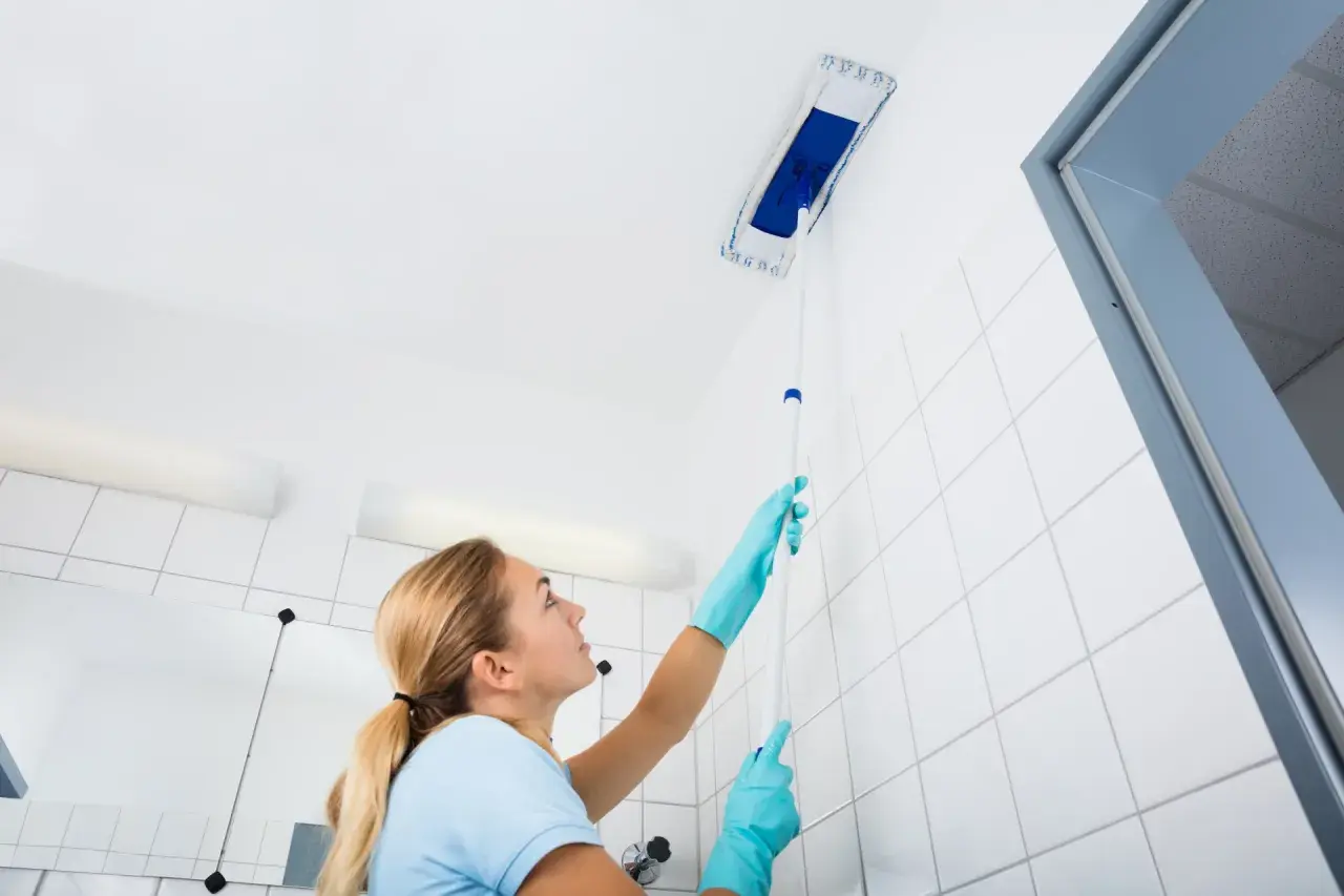 Femme nettoyant le plafond avec une raclette. Le sens de pose du lambris PVC au plafond est important pour un résultat impeccable.
