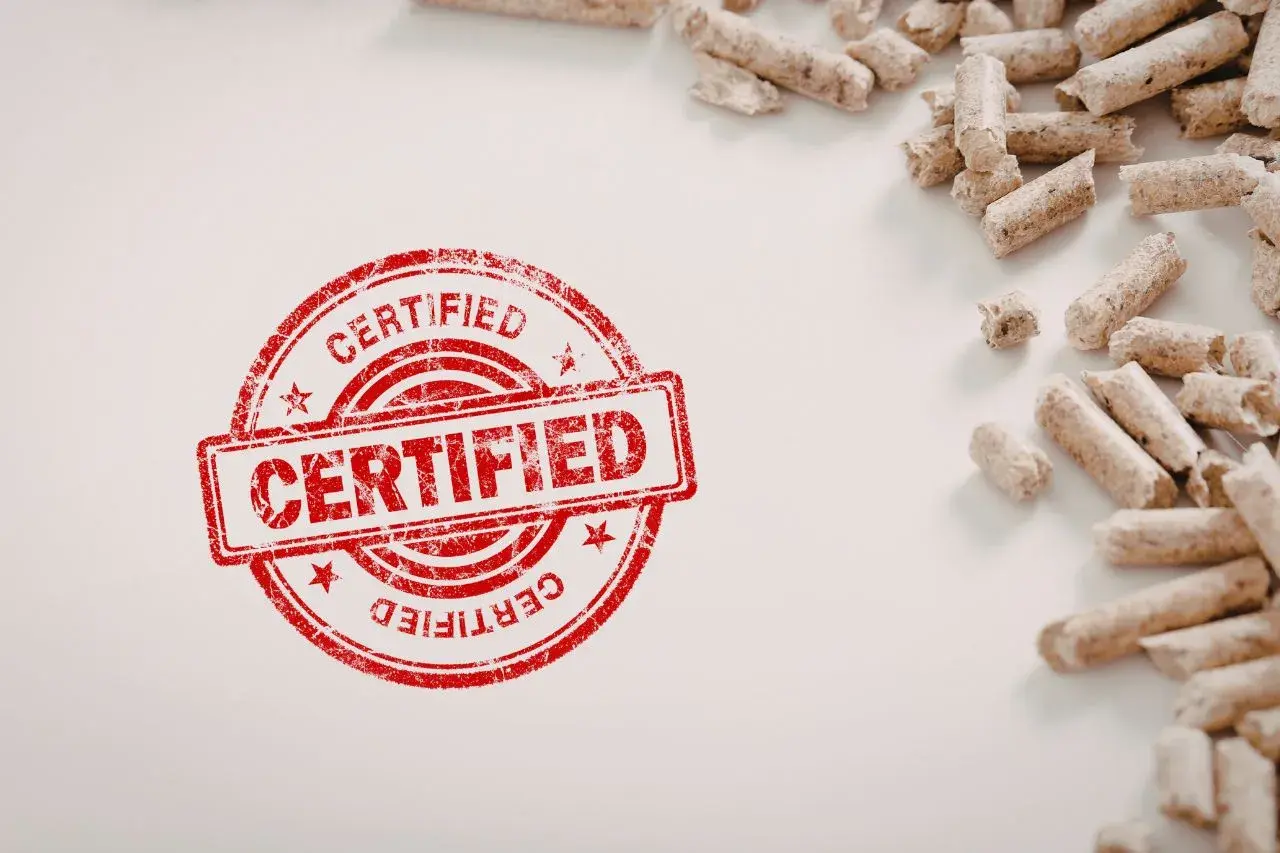 Certyfikowany pellet, potwierdzający, że pellet jest odnawialnym źródłem energii, leży obok czerwonego stempla.