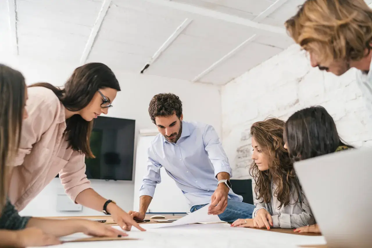 Equipo colaborando en un proyecto, demostrando un alto coeficiente emocional al comunicarse y resolver problemas juntos.