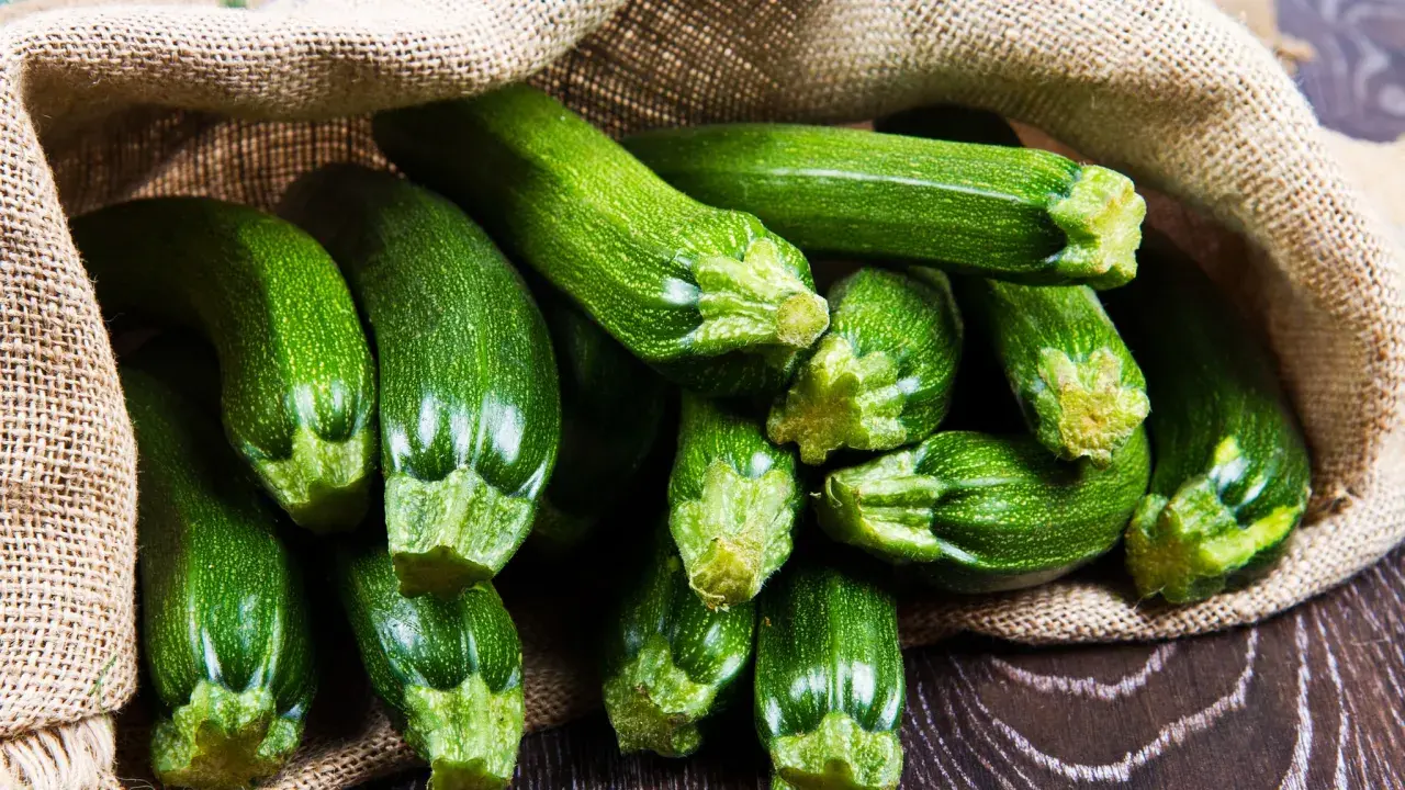 Frische, grüne Zucchini quellen aus einem Jutesack. Diese gesunde Gemüsesorte ist perfekt für leichte und nahrhafte Gerichte.
