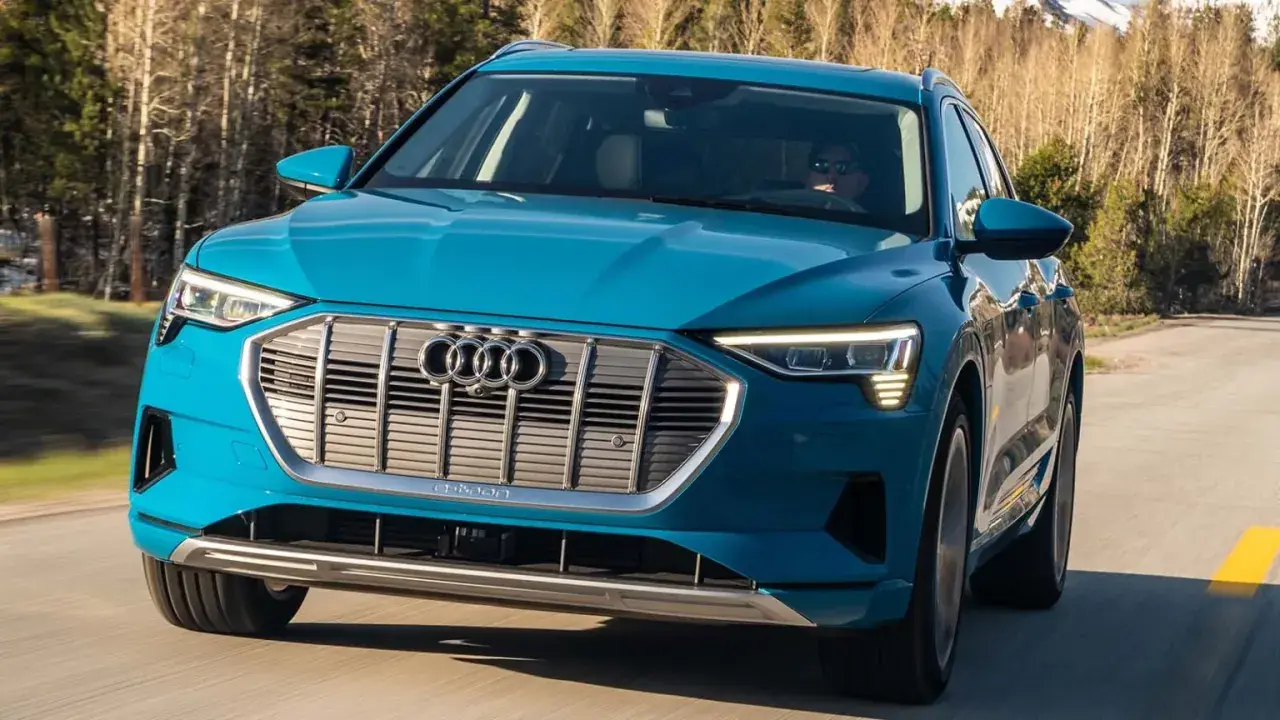 Blå Audi e-tron kör på en väg i skogen. En begagnad Audi e-tron som är perfekt för äventyr.