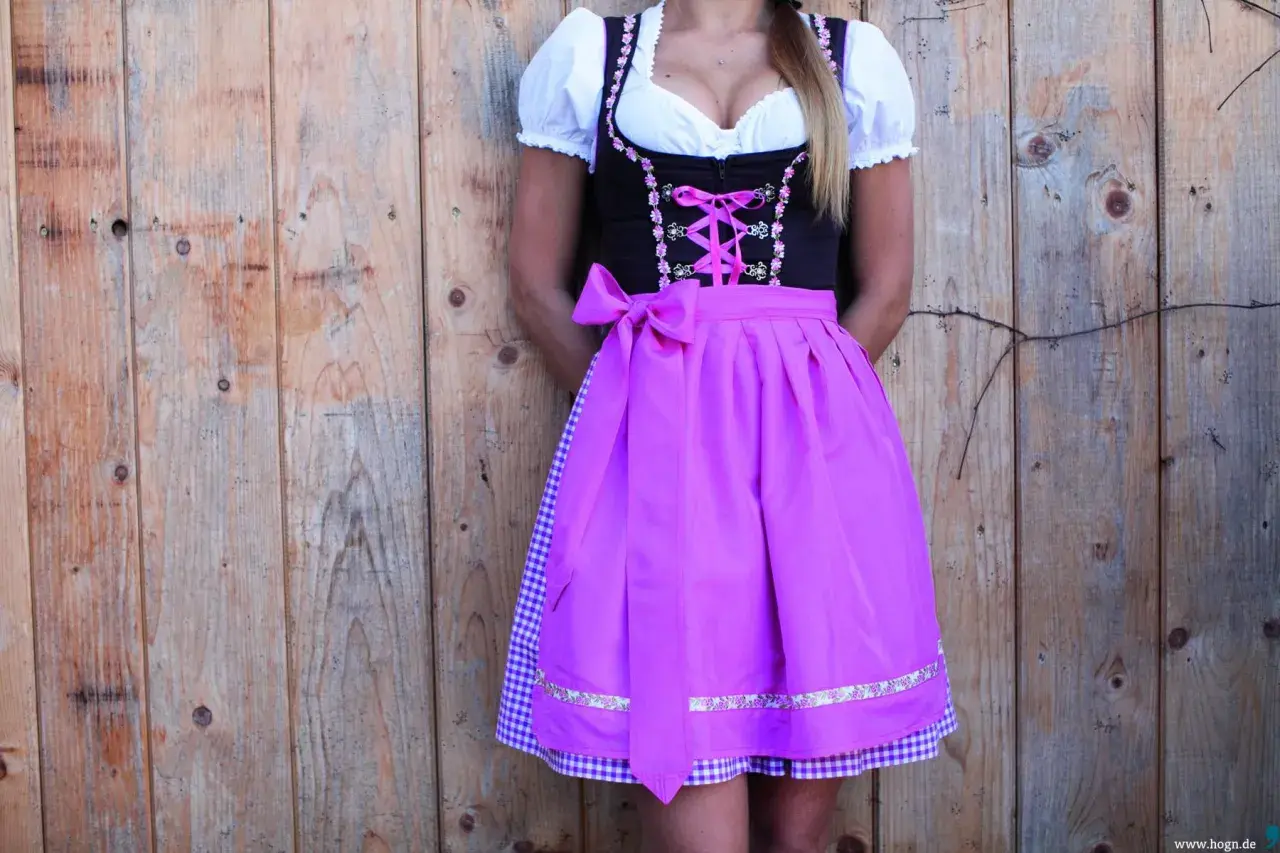 Dirndl mit pinkem Satinband-Schnürung und passender Schleife. Darunter ein karierter Unterrock.