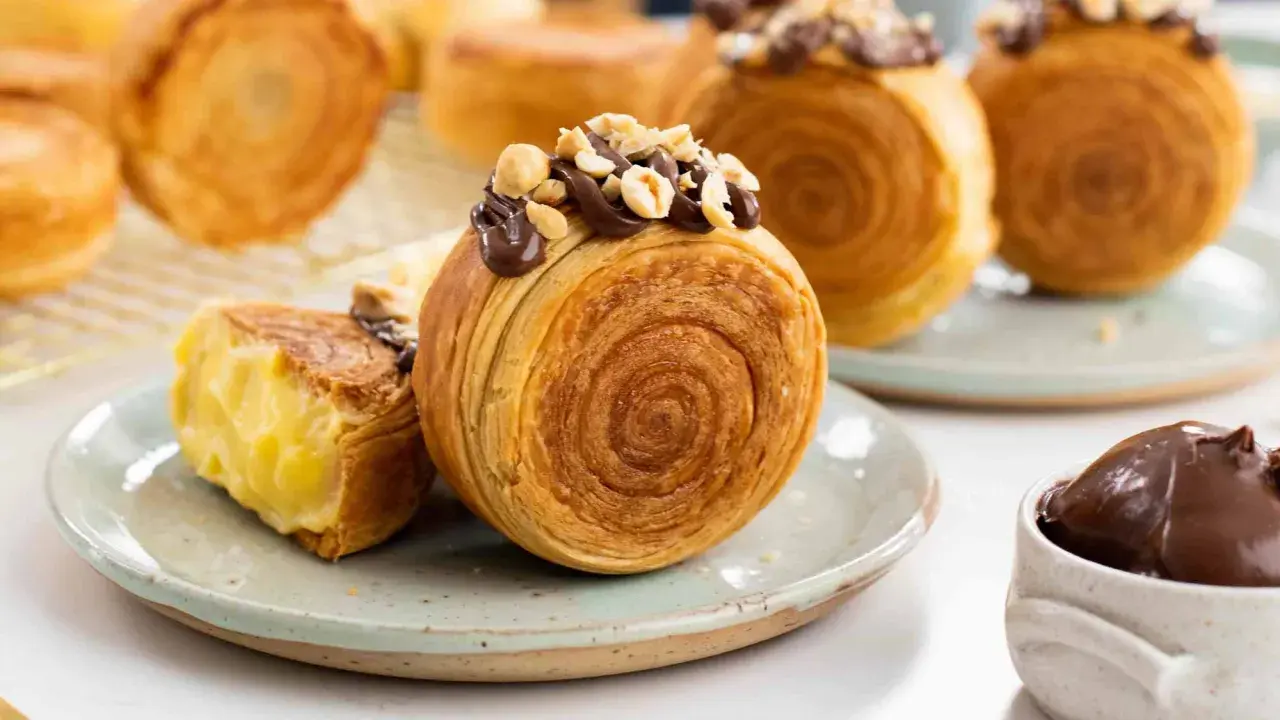 Deliziosi dolci francesi, croissant a spirale ripieni di crema e guarniti con cioccolato e nocciole.
