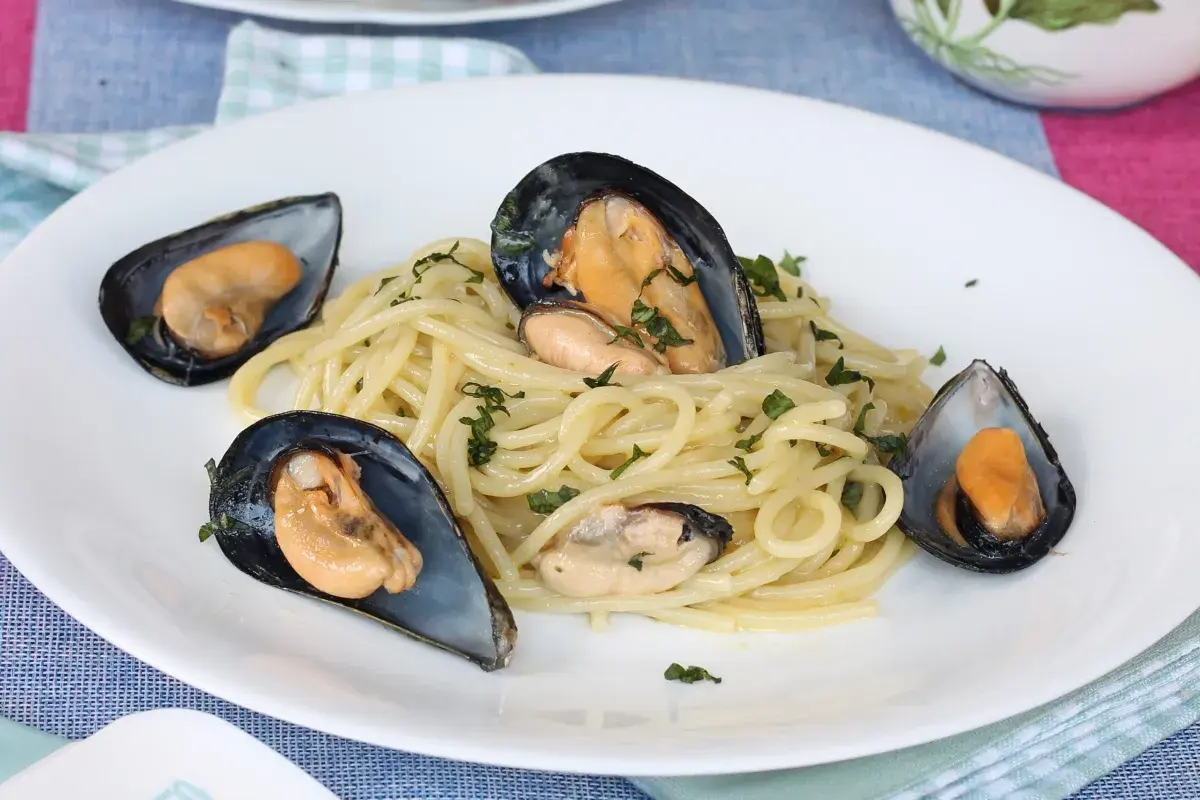 Spaghetti con le cozze in bianco, un piatto semplice e gustoso, con cozze fresche e prezzemolo tritato.