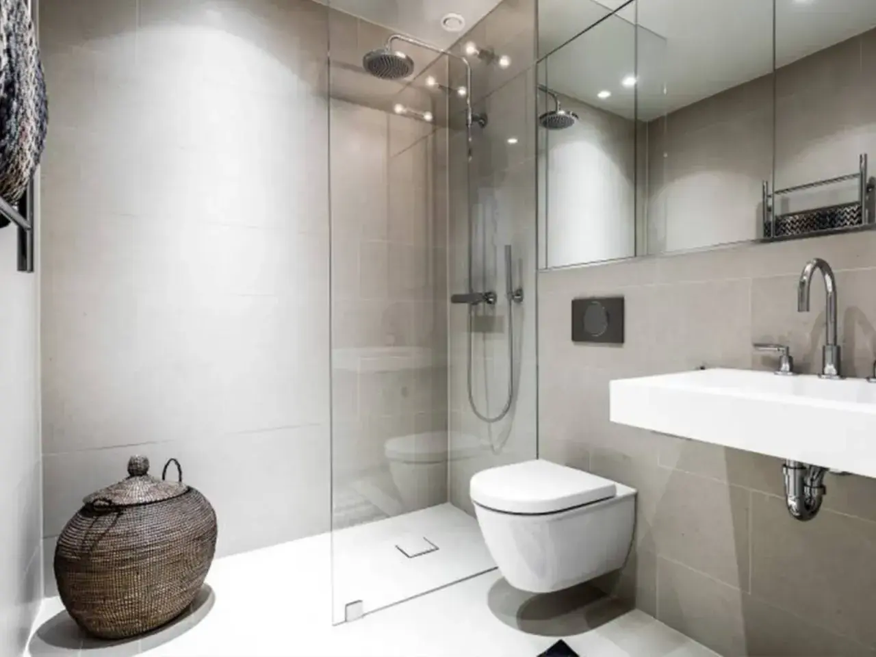 Moderno bagno senza finestra con doccia a filo pavimento, WC sospeso, lavabo minimalista e cesto in vimini.