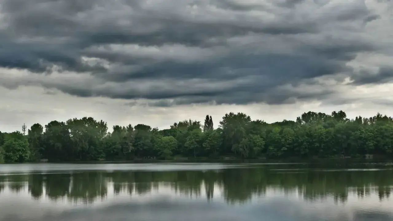Ciemne chmury zapowiadają biały szkwał nad spokojną taflą jeziora.