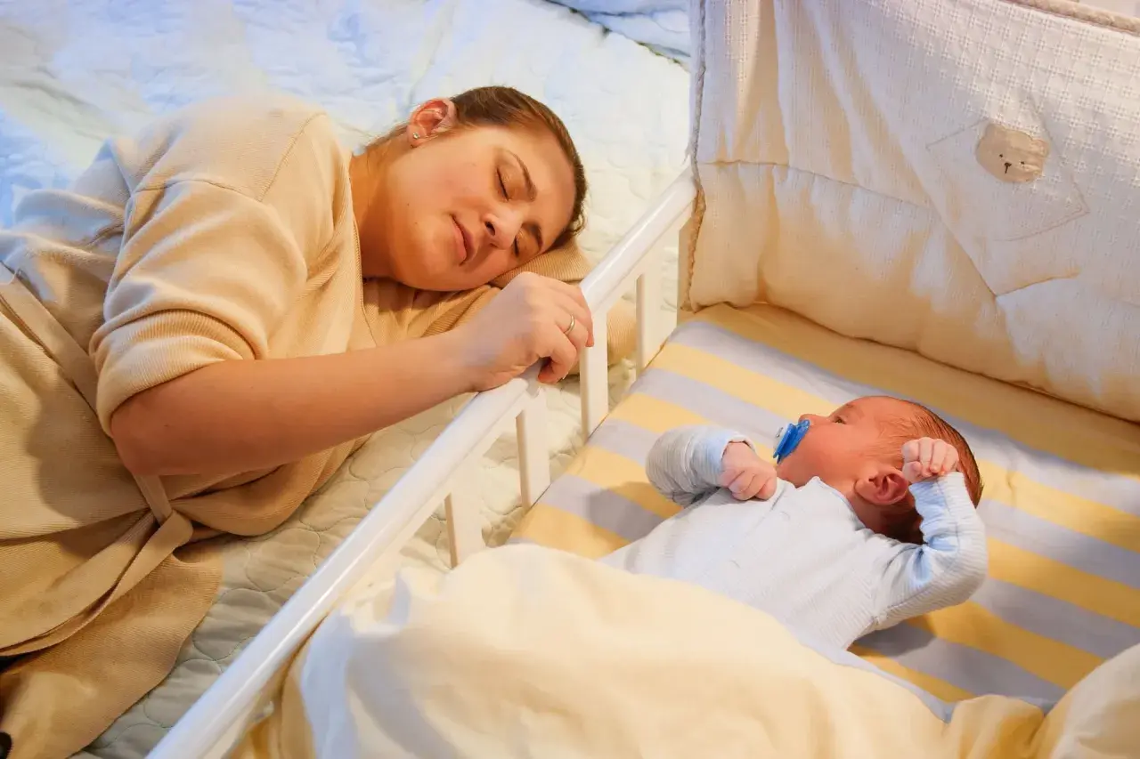 Mamma dorme accanto al lettino dove un bambino di 2 anni si sveglia piangendo disperato.