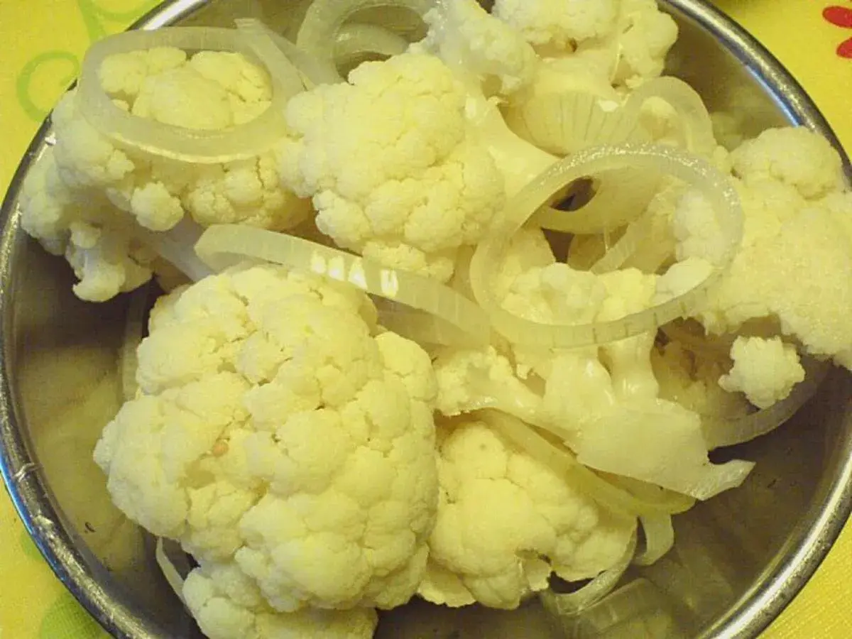 Blumenkohl und Zwiebelringe für blumenkohl sauer einlegen in einer Schüssel.