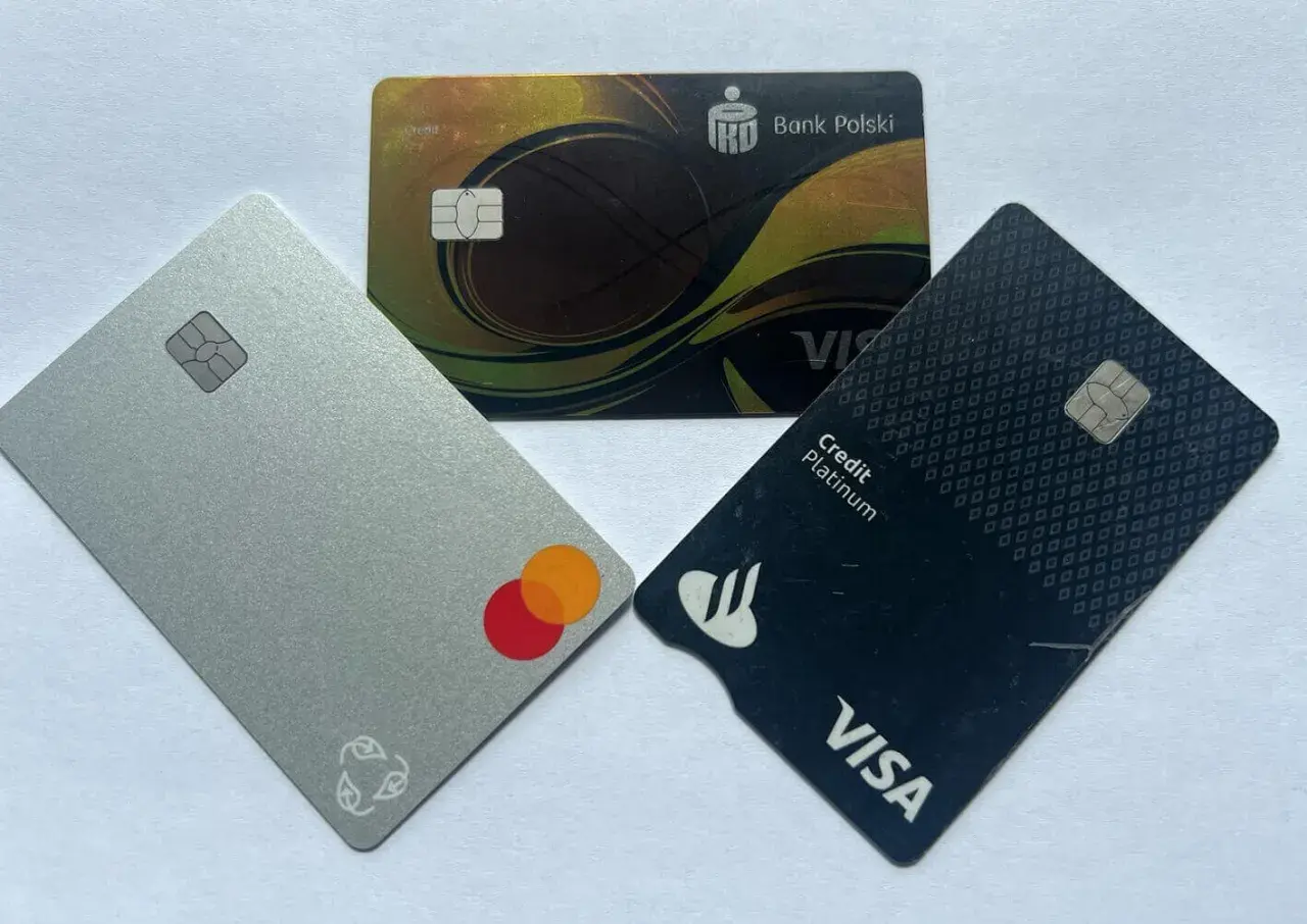 Trzy karty płatnicze: srebrna z logo Mastercard, czarna z logo Visa Credit Platinum i złota z logo Banku Polskiego.