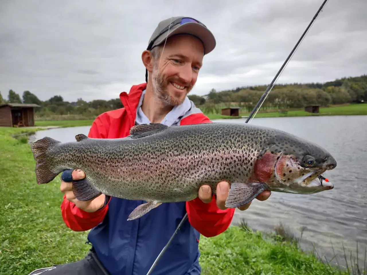 Glücklicher Angler hält stolz einen großen Regenbogenforelle, ein toller Fang beim LImfjord angeln.