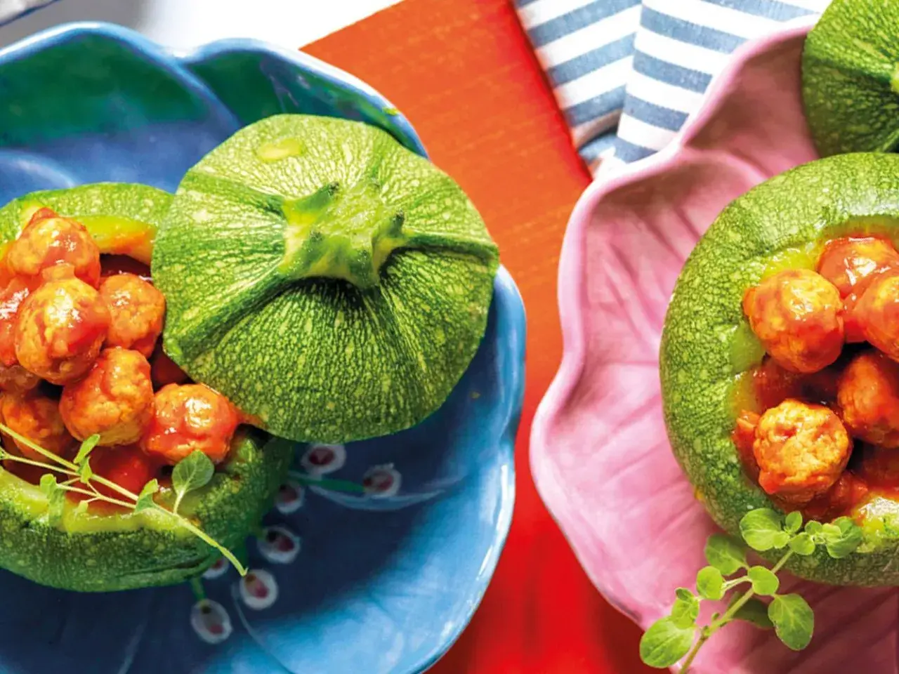 Zucchine tonde ripiene di polpettine in salsa, servite in ciotole colorate. Un piatto invitante e gustoso.