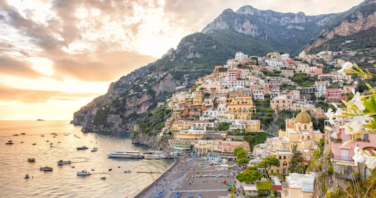 A stunning view of Positano, perfect for your Amalfi Coast 2-day itinerary. Colorful houses cascade down a steep cliff to a beach dotted with boats.