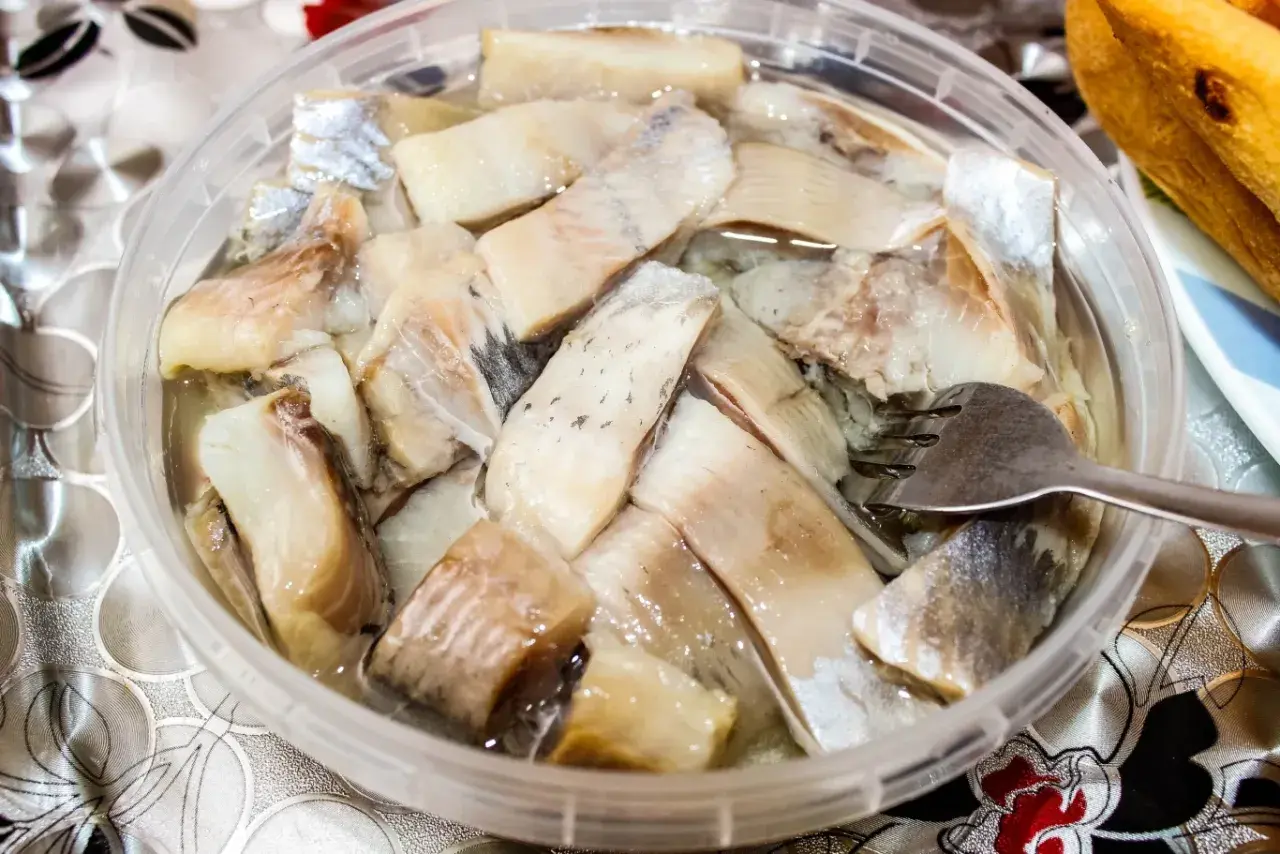 Pyszne śledzie na wielkanoc w zalewie, gotowe do podania. Widoczna jest też część bagietki.