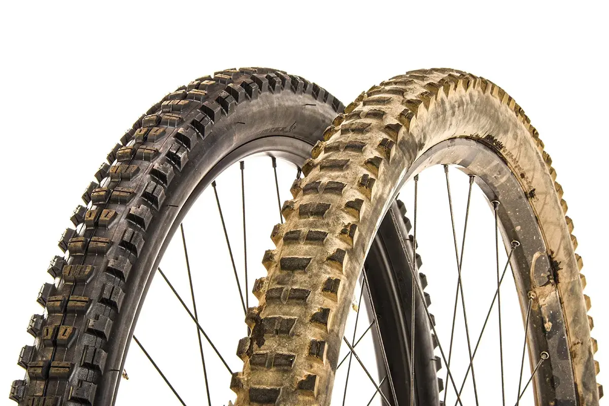 Two mountain bike tires, one new and one worn, illustrate when to replace mountain bike tires.