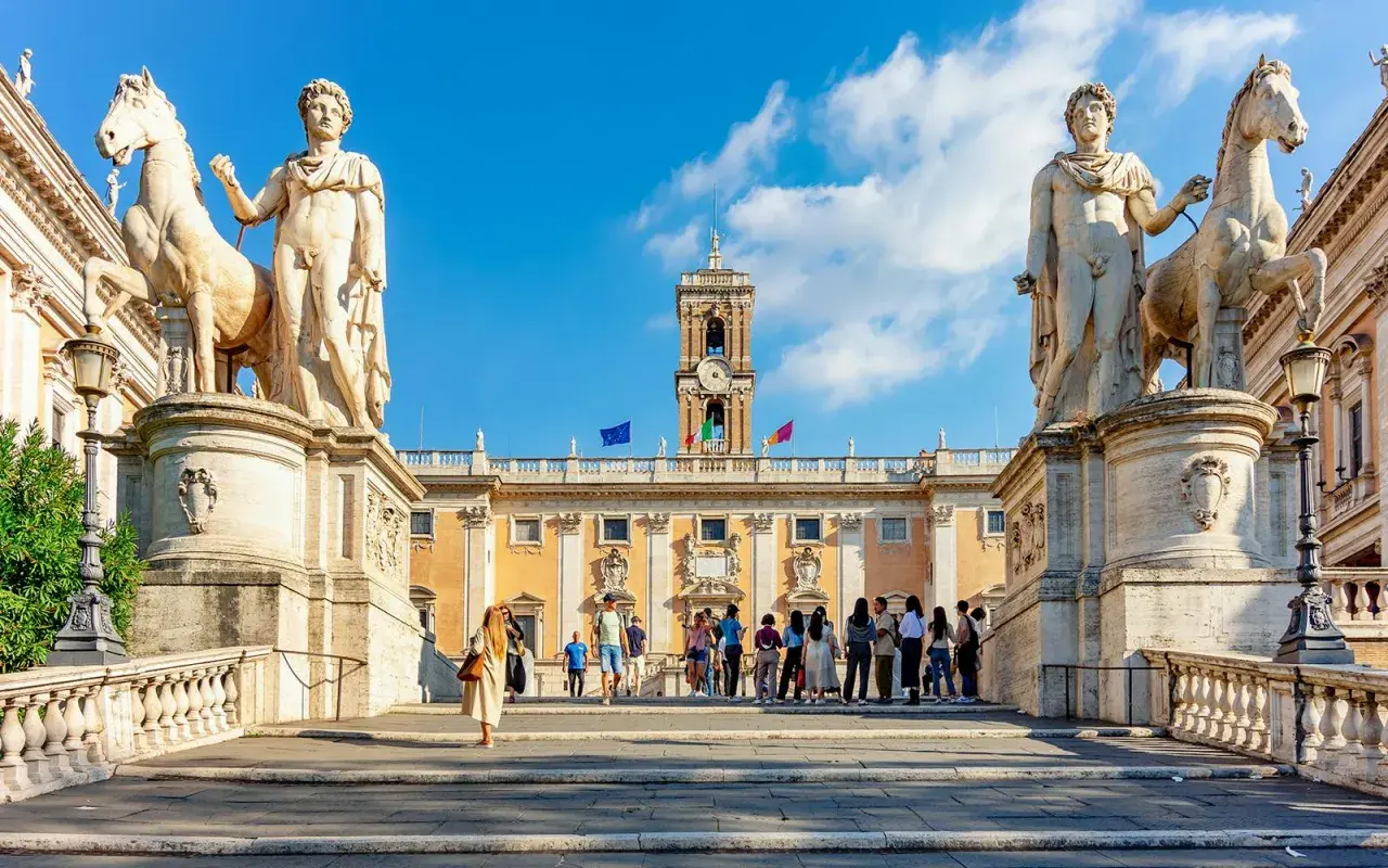 Devant les musées du Capitole, des statues équestres majestueuses encadrent une foule admirative.