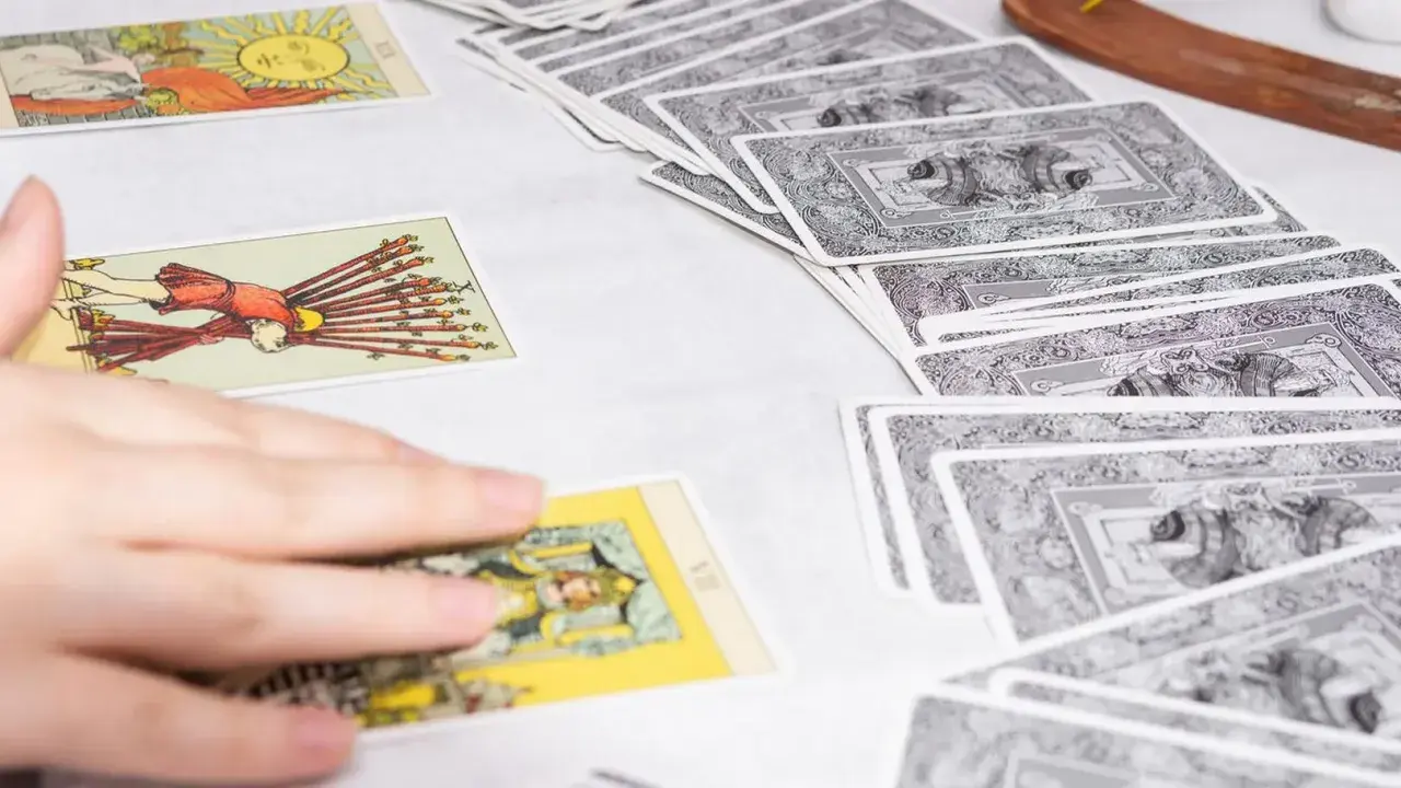 Tarot tygodniowy Skorpion: rozłożone karty tarota, ręka wybiera jedną z nich.