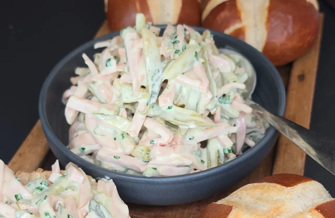 Ein cremiger Fleischsalat, perfekt für ein schnelles **Fleischsalat Rezept**. Serviert mit Laugenbrötchen.