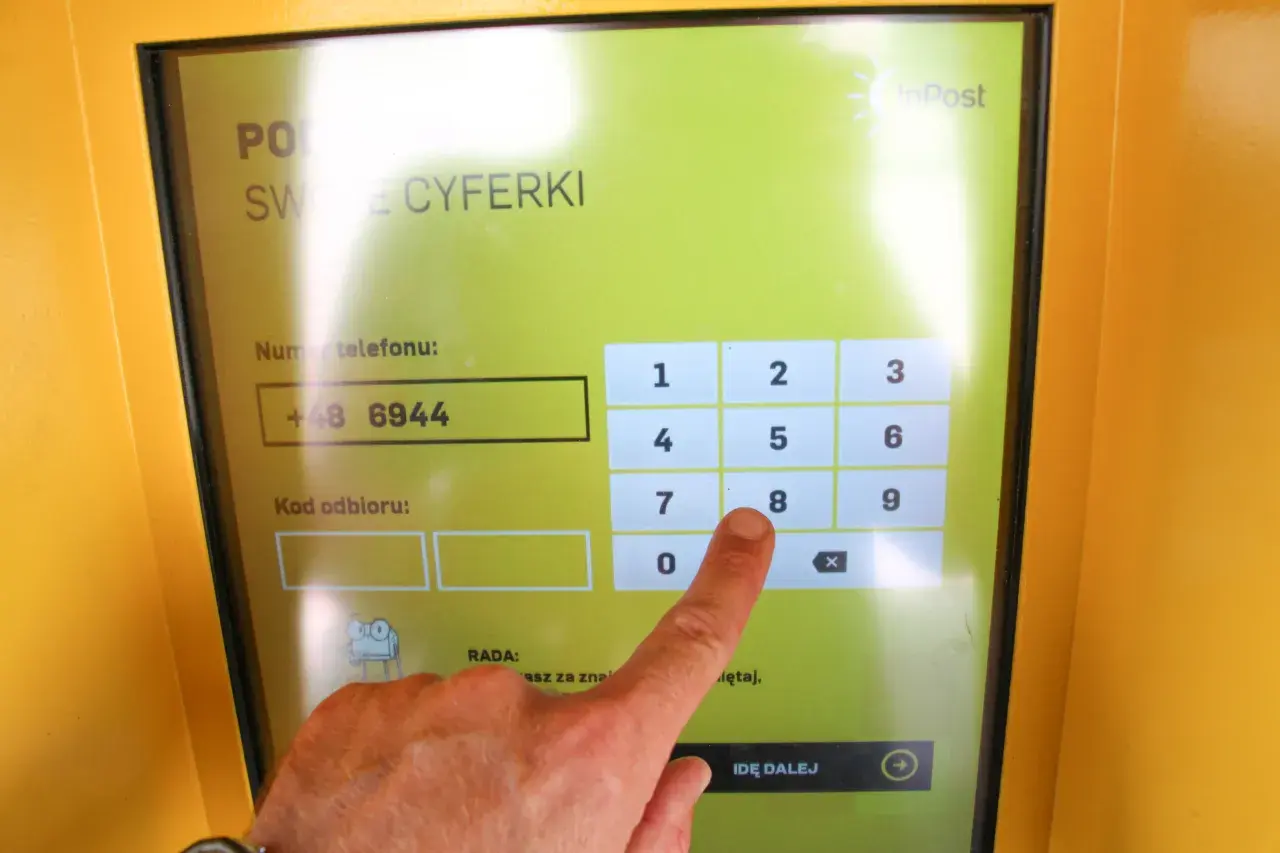 Palec wskazujący naciska cyfrę 8 na ekranie paczkomatu InPost.