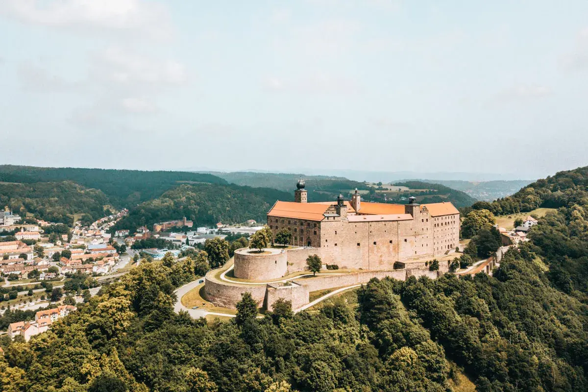 Die Plassenburg thront über der Kulmbach Altstadt, umgeben von grünen Hügeln. Ein malerischer Anblick!