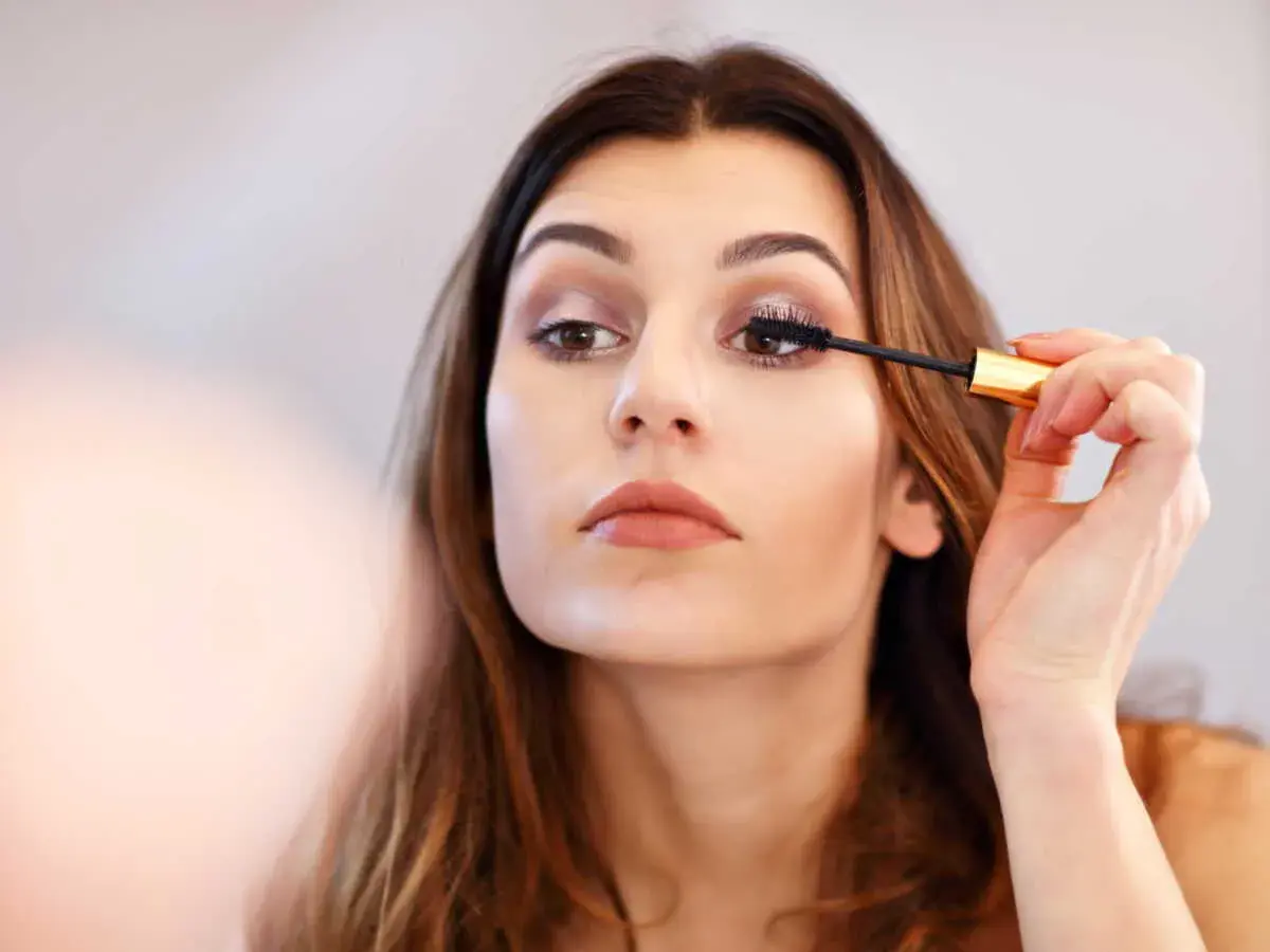 Une femme applique du mascara sur ses cils. Elle apprend comment mettre du mascara pour un regard intense.