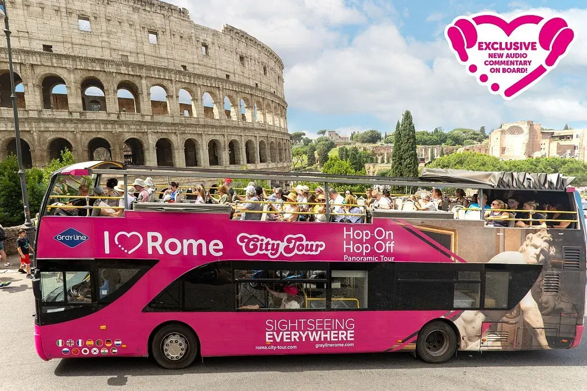 Bus touristique rose "I ❤️ Rome City Tour" près du Colisée. Profitez d'un plan de bus touristique pour explorer Rome.