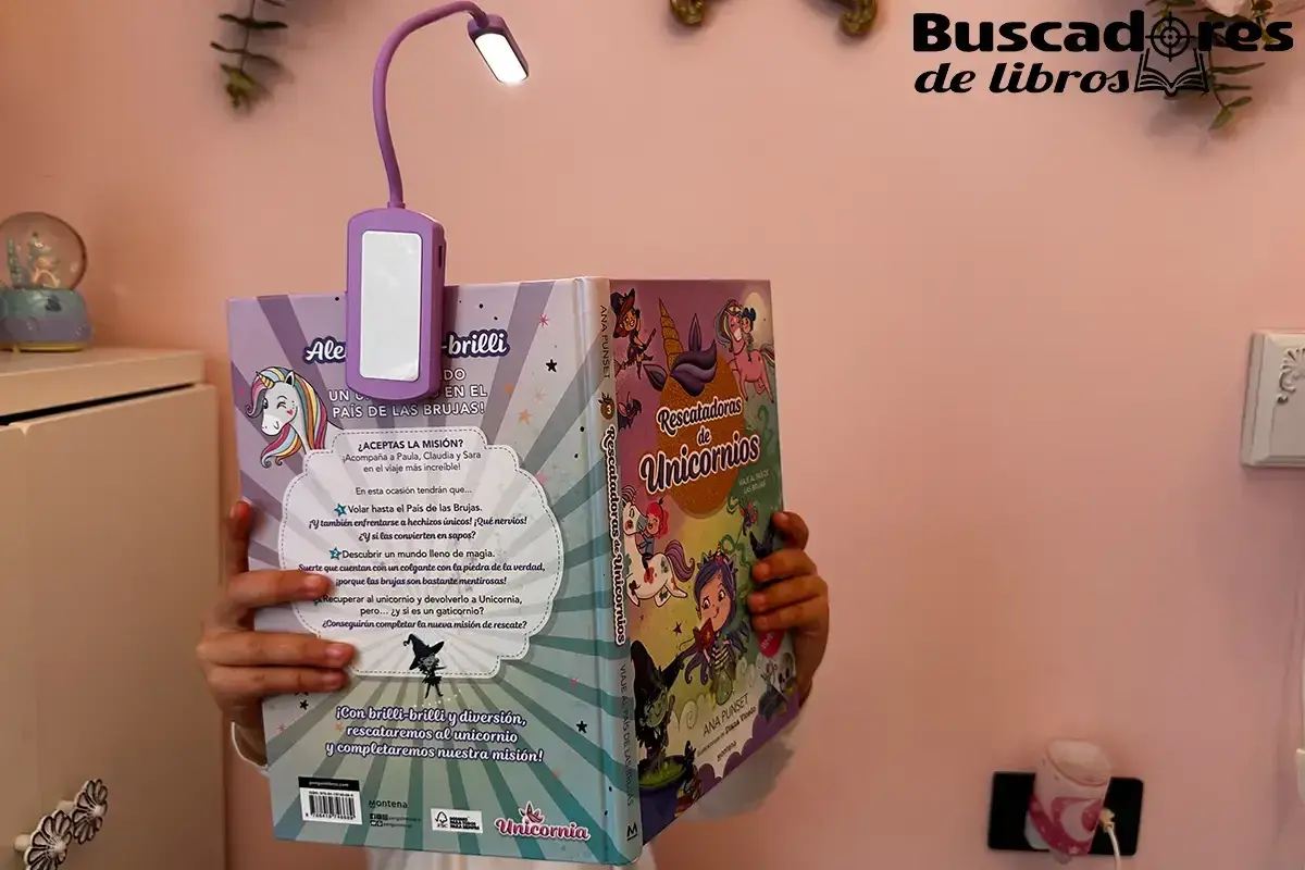 Una lampara brazo articulado ilumina un libro de unicornios.