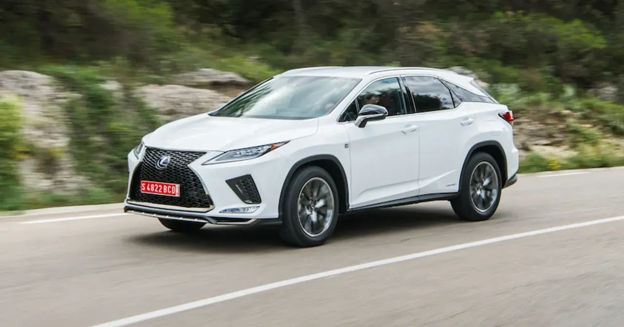 Biały Lexus RX 300 pędzi po krętej drodze wśród zielonych wzgórz.