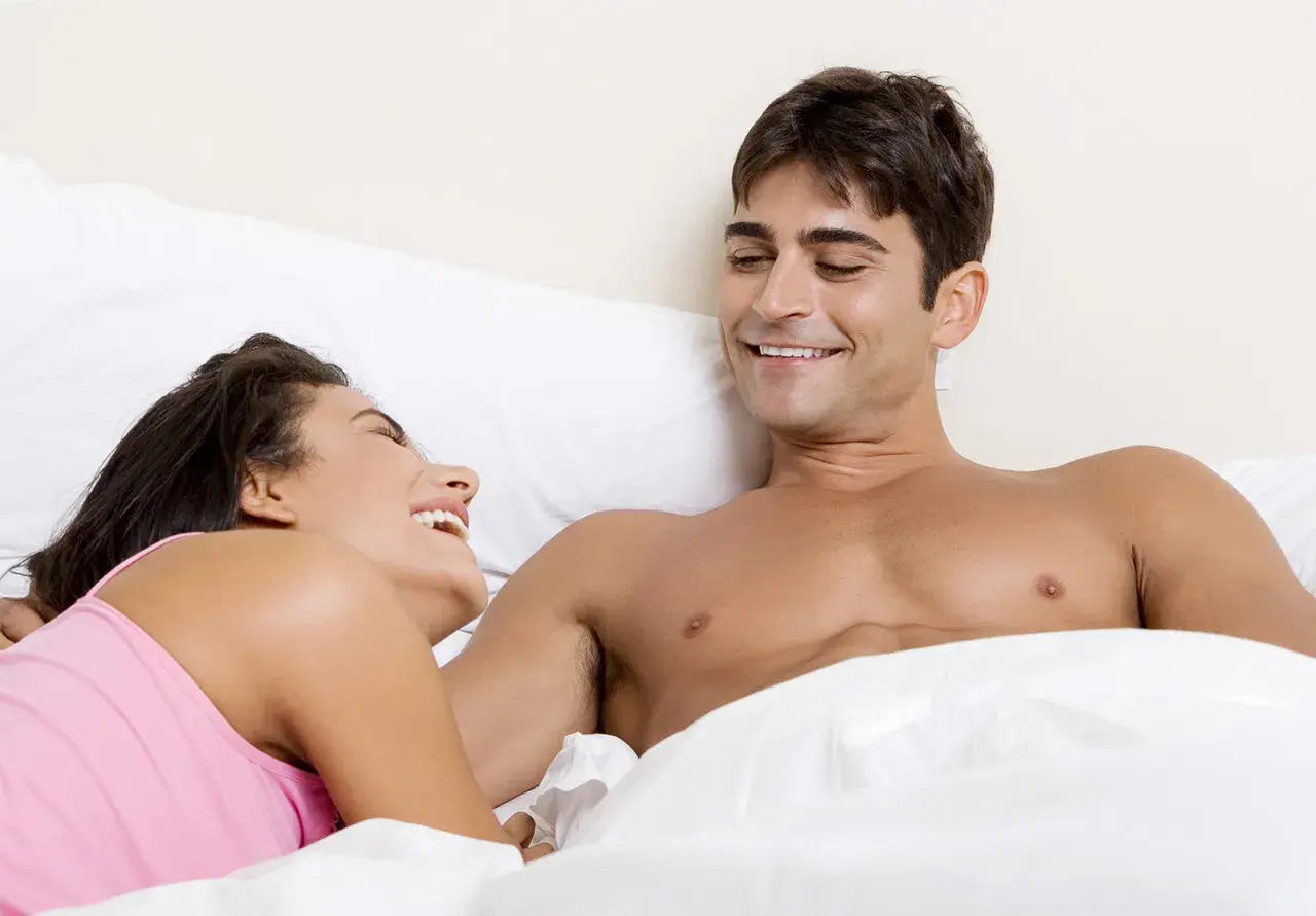 Coppia sorridente a letto, complici e felici. Momenti intimi tra amici del sesso.