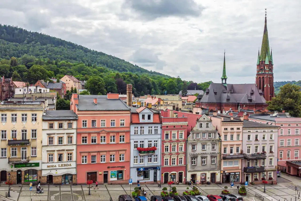 Kolorowe kamienice i kościół z zieloną wieżą tworzą malowniczy krajobraz. Odkryj teraza ruda atrakcje, spacerując po urokliwym rynku.
