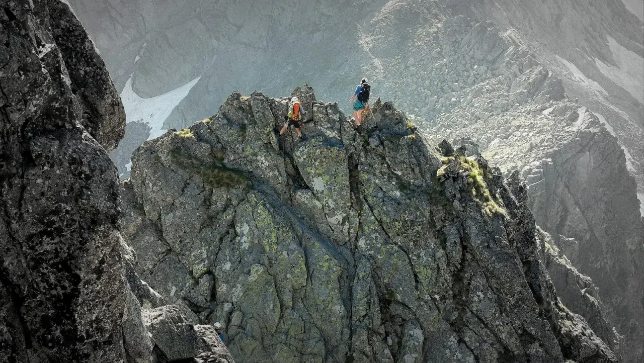 Dwóch alpinistów pokonuje skalisty grzbiet. Jeden z nich schodzi po linie, drugi obserwuje. To trudna droga Martina na Gerlach.