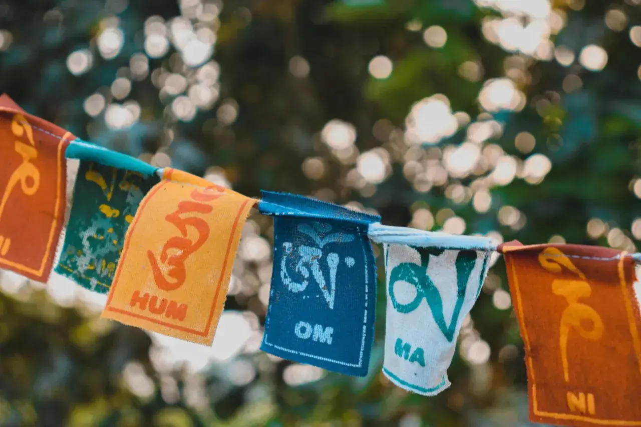Kolorowe chorągiewki z buddyjskimi symbolami i słowami, jak "Om" i "Hum", tworzą wizualną mantrę.