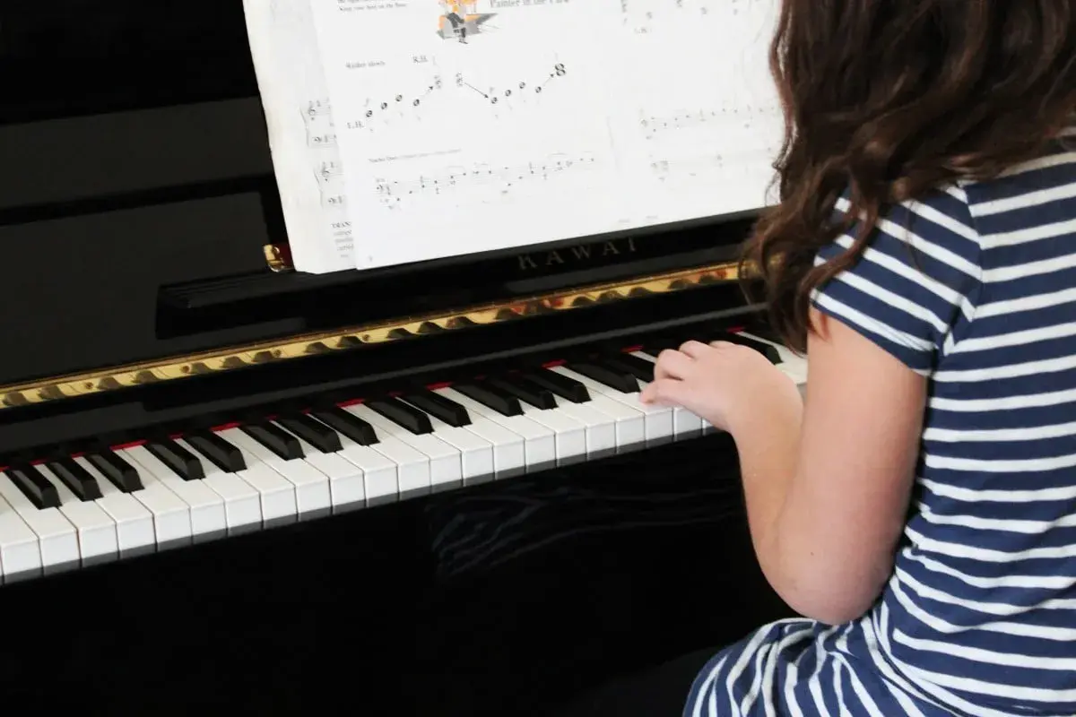 Une jeune fille joue du piano, ses doigts effleurant les touches pour créer une douce mélodie adagio musique.