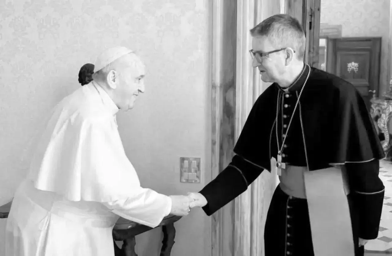 Papst Franziskus, seit wann ist Franziskus Papst, schüttelt einem Bischof die Hand.