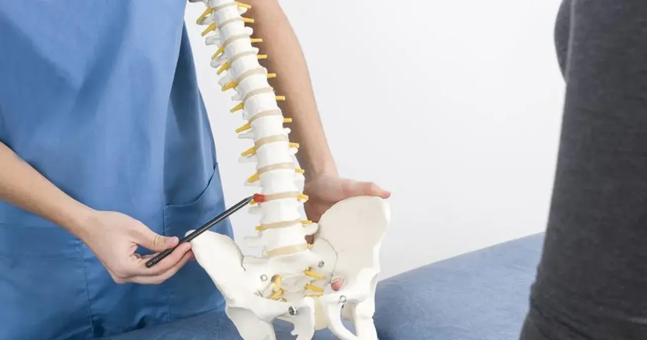 Fizjoterapeuta pokazuje model kręgosłupa, omawiając wpływ torbieli pajęczynówki na wysiłek fizyczny.