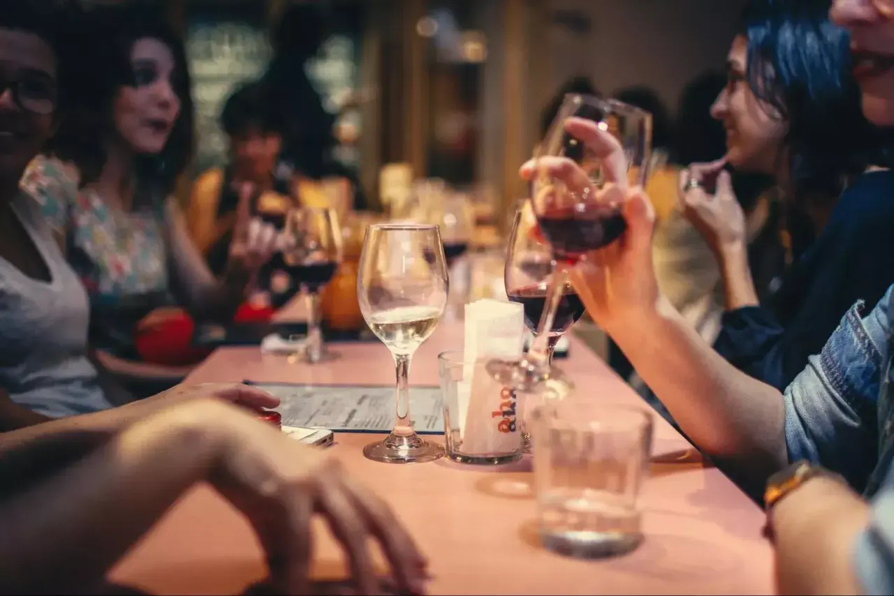 Amis partageant un bon type vin rouge et blanc autour d'une table rose.