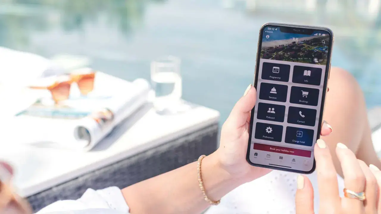 Frau nutzt Handy-App, um eine TUI Reise zu stornieren. Auf dem Bildschirm sind Optionen wie "Bookings" und "Change hotel" sichtbar.
