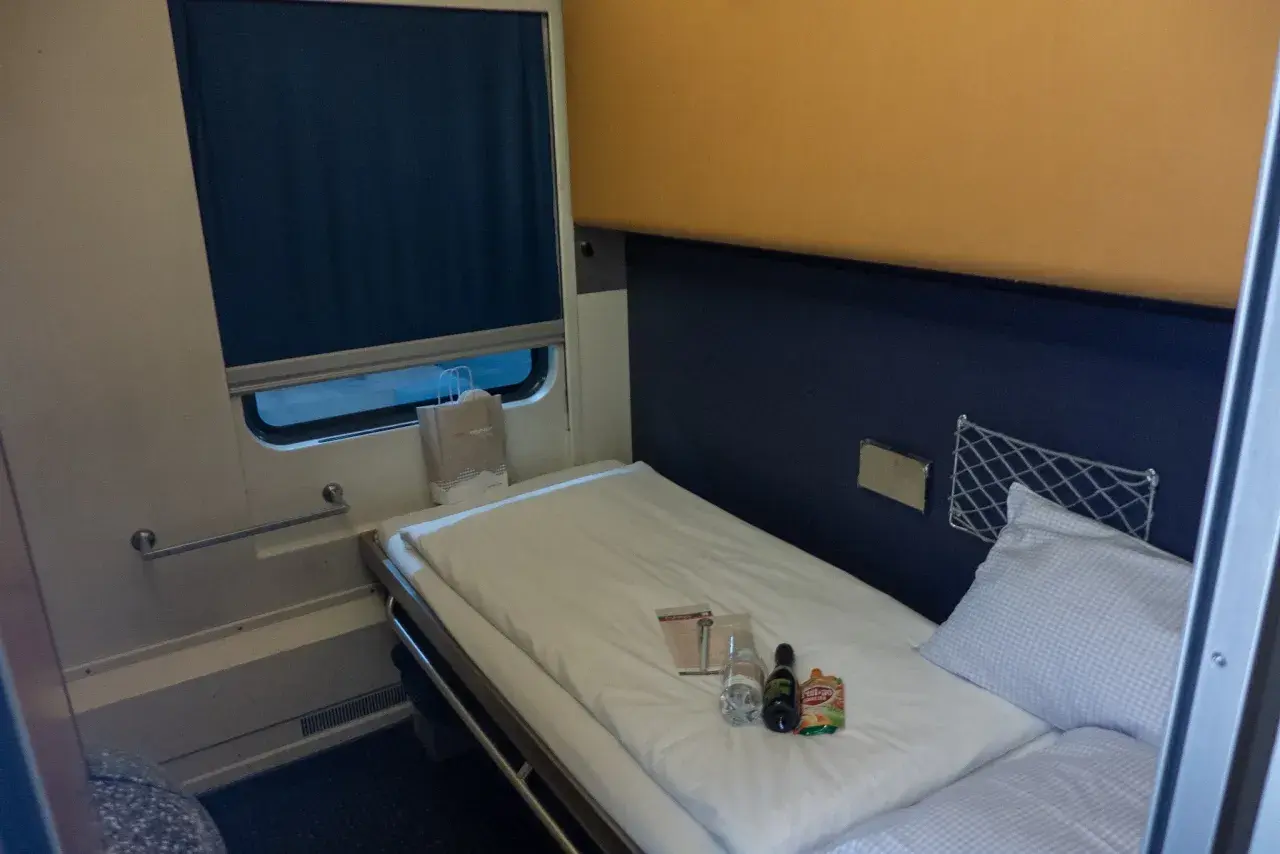 Gemütliches Bett im Nachtzug Berlin Wien. Kleine Flaschen und eine Tüte liegen bereit.