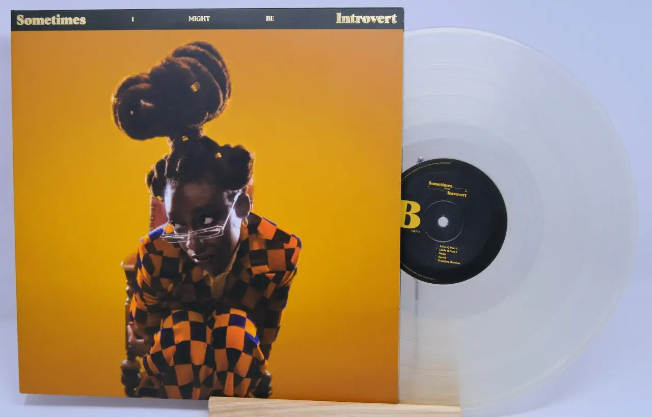 Little Simz, czasem introvert, na okładce płyty "Sometimes I Might Be Introvert". Obok przezroczysta winylowa płyta.