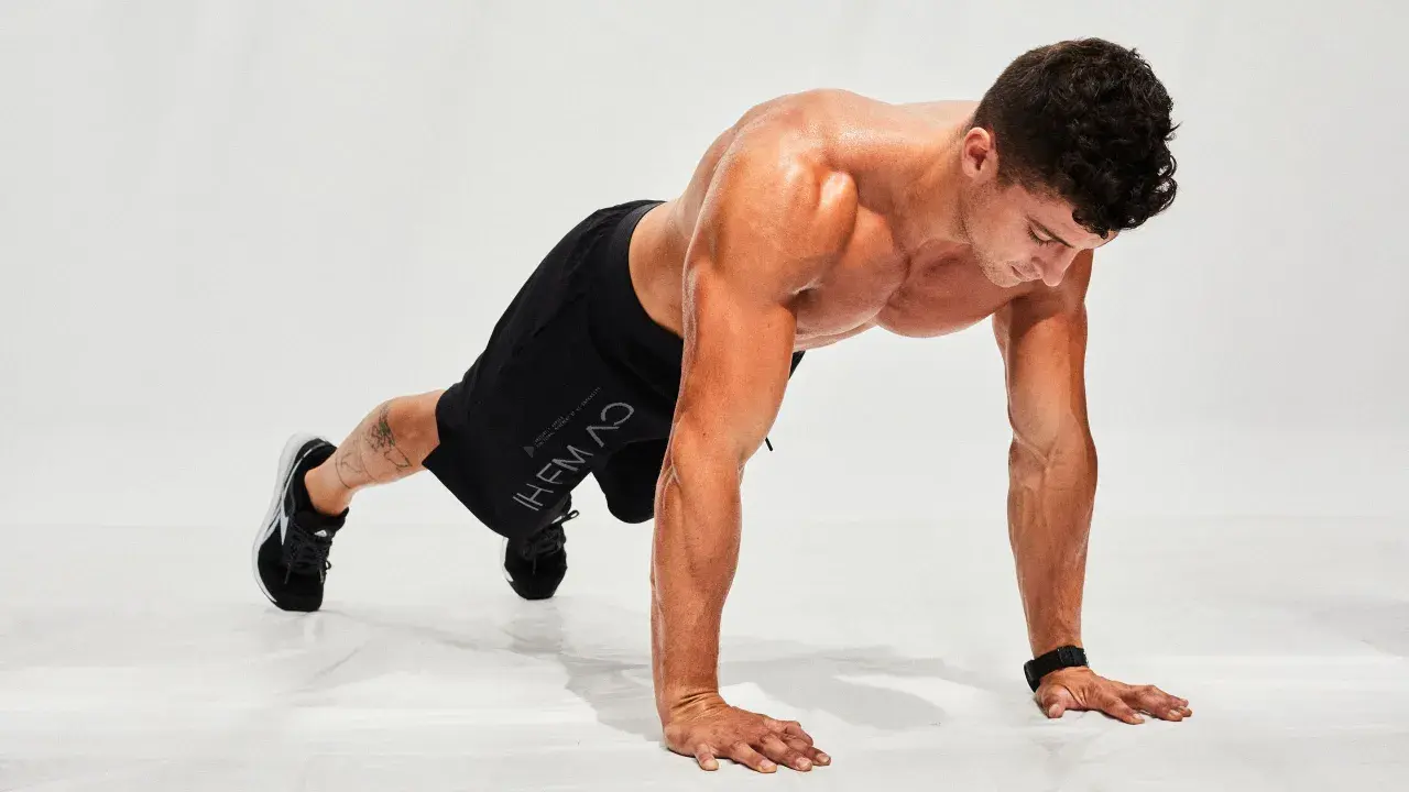 Hombre haciendo flexiones en posición de plancha, listo para un entrenamiento de **hiit en casa**.