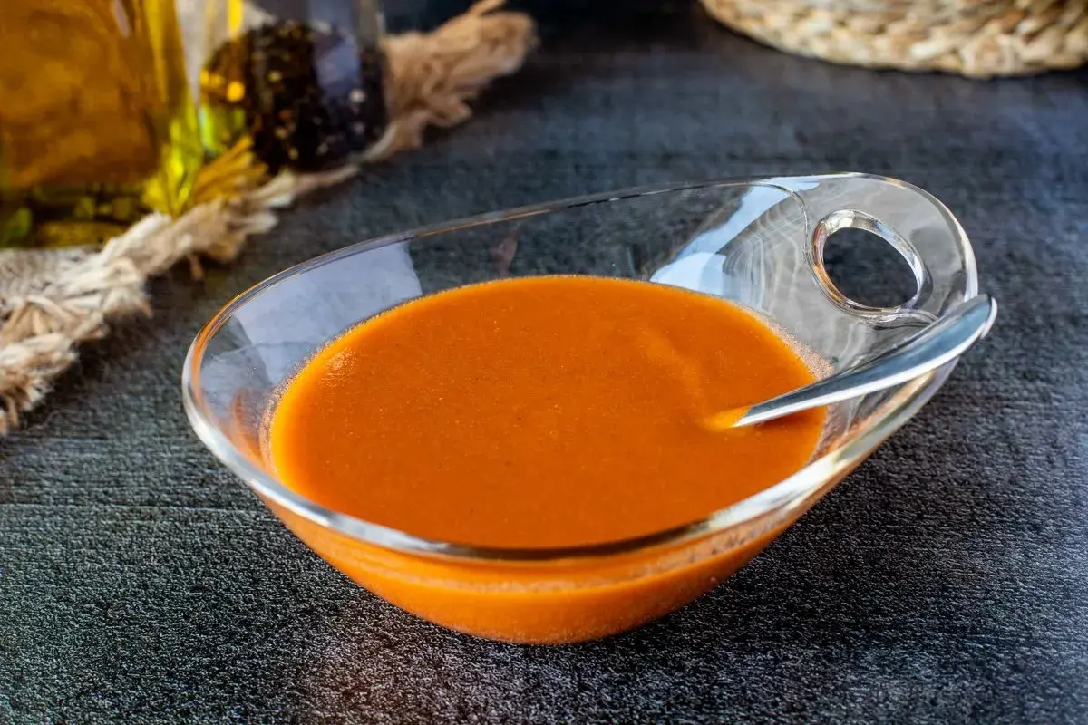 Un cuenco de cristal con una deliciosa salsa americana anaranjada, lista para acompañar tus platos.