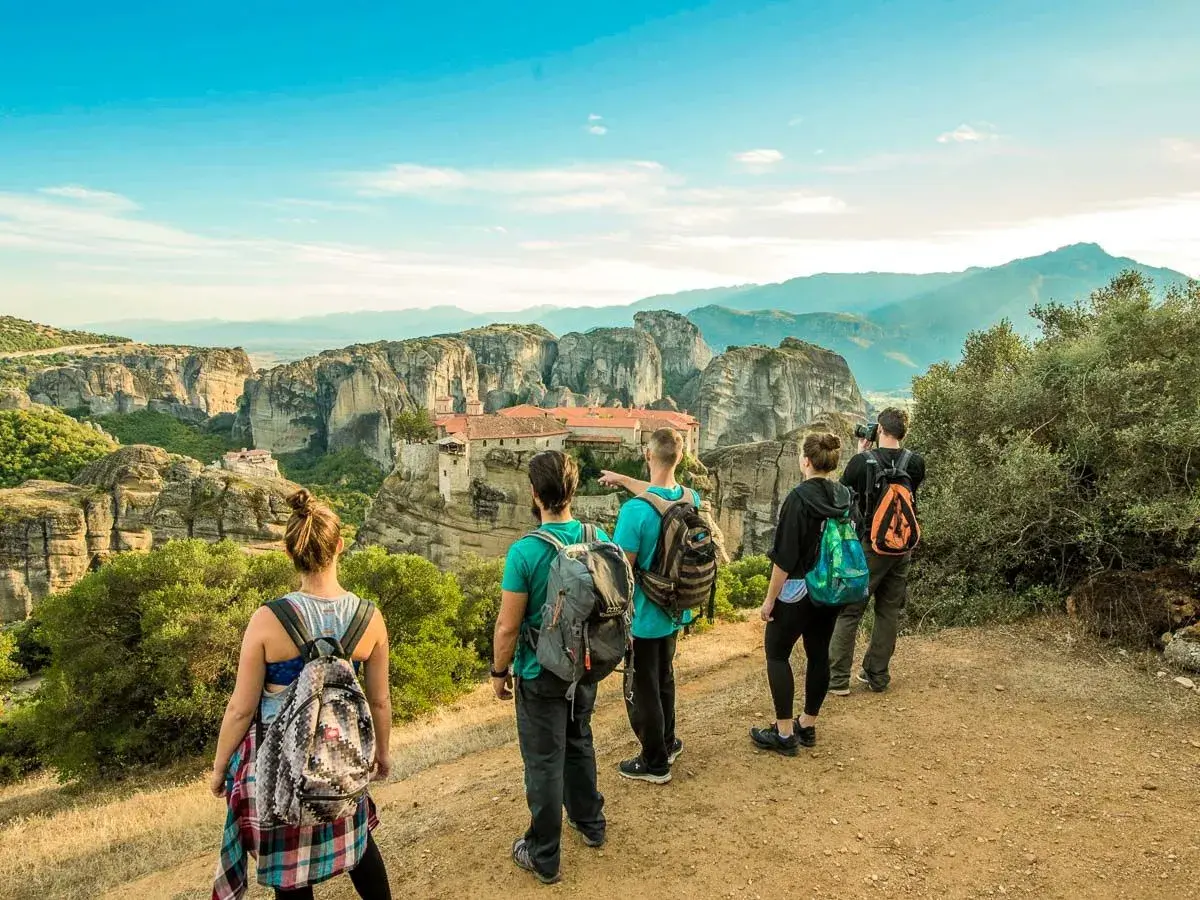 Hikers admire the stunning monasteries of Meteora, Greece, from a scenic viewpoint. The group enjoys a breathtaking vista during their hiking adventure.