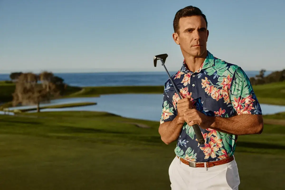 Ein Mann mit einem bunten Polohemd und einem Golfschläger auf einem Golfplatz.