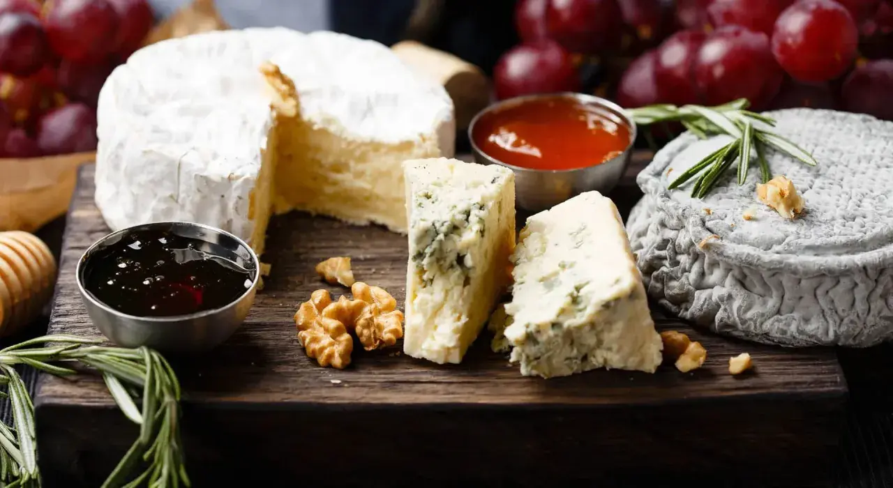 Assaggio di formaggi: un cremoso, un erborinato con venature blu e un formaggio grigio. Accompagnati da noci, miele e uva rossa.